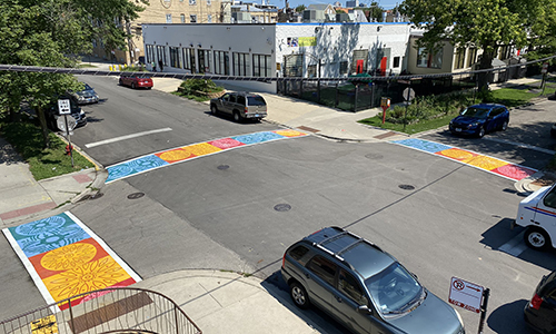 Aerial view of intersection with three brightly painted decorative crosswalks